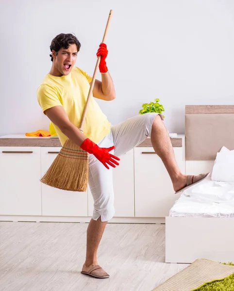 Jonge knappe man schoonmaken in de slaapkamer — Stockfoto
