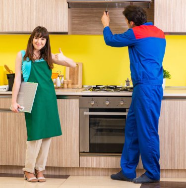 Mutfakta müteahhitle birlikte çalışan bir kadın tamir hakkında konuşuyor.