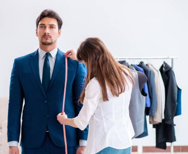 Profesyonel terzi resmi kıyafet için ölçü alıyor.