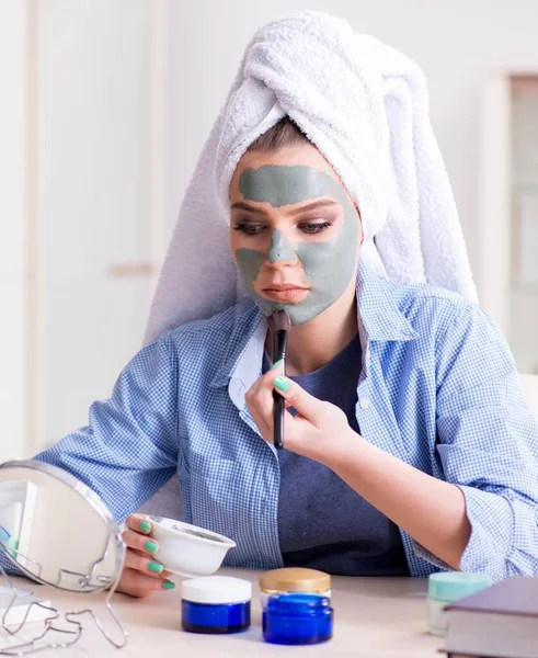 Frau trägt Tonmaske zu Hause mit Pinsel auf — Stockfoto