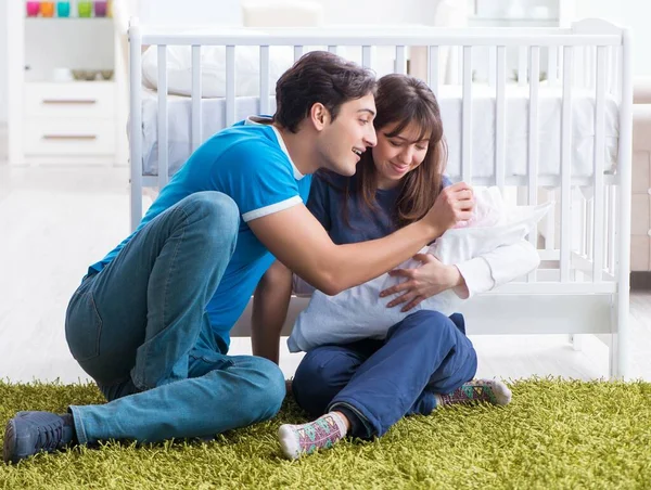 Молодые родители с новорожденным ребенком сидят на ковре — стоковое фото