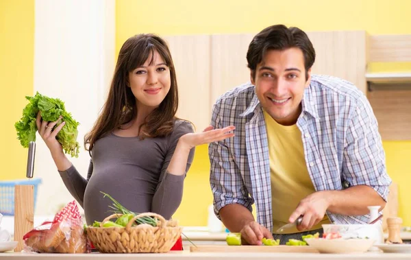 Man en zwangere vrouw het bereiden van salade in keuken — Stockfoto