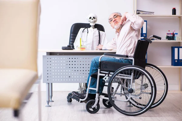 Staruszek na wózku inwalidzkim odwiedza martwego lekarza — Zdjęcie stockowe
