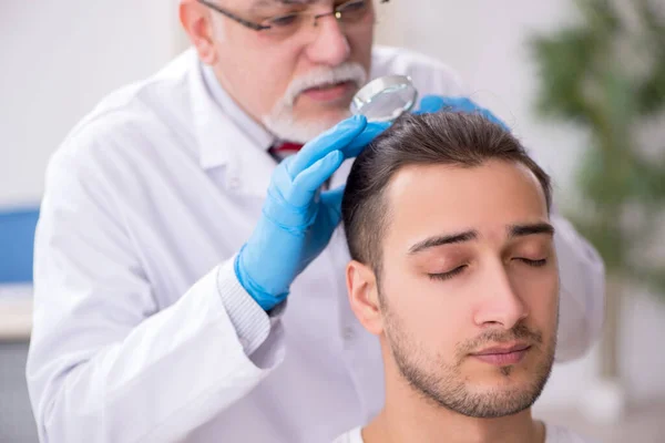 Homem jovem visitando médico dermatologista experiente — Fotografia de Stock