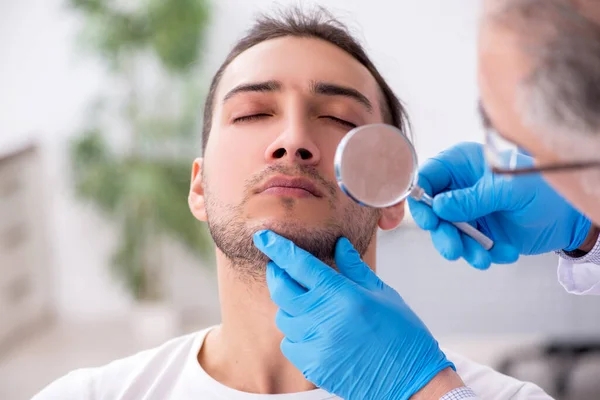 Homem jovem visitando médico dermatologista experiente — Fotografia de Stock