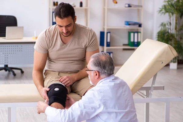 Experienced doctor traumatologist examining young male patient — Stock Photo, Image