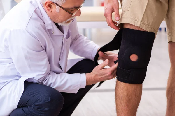 Médico traumatólogo experimentado examinando paciente varón joven —  Fotos de Stock