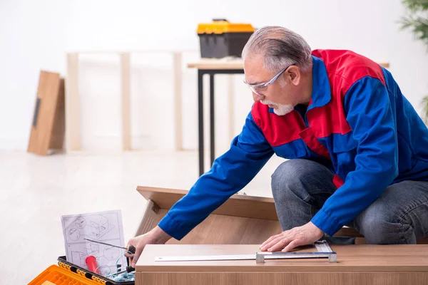 Old male carpenter working indoors