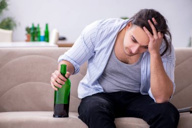 Genç alkolik erkek evde şarap içiyor.