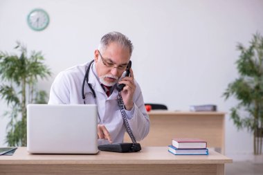 Klinikte çalışan yaşlı erkek doktor.