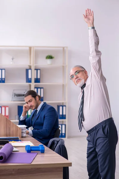 Twee werknemers doen fysieke oefeningen op de werkplek — Stockfoto