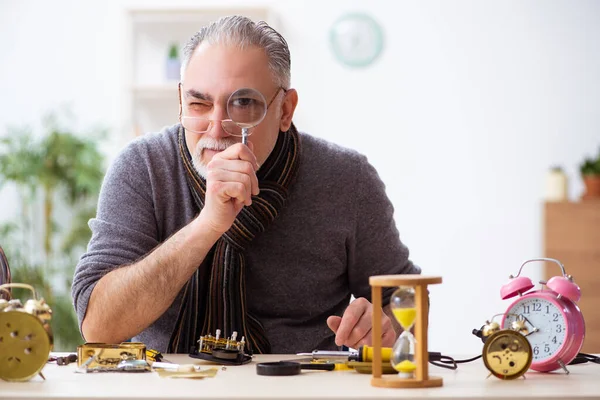 Atölyede çalışan yaşlı bir erkek saatçi.