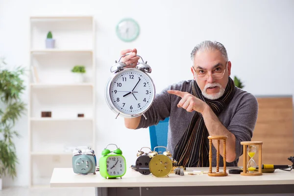 Atölyede çalışan yaşlı bir erkek saatçi.