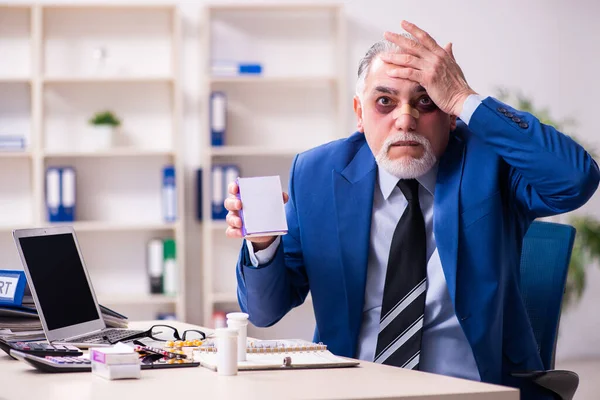 Viejo cara lesionado empleado sentado en la oficina — Foto de Stock