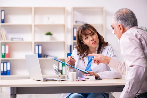 Velho visitando jovem médico feminino para cirurgia plástica — Fotografia de Stock