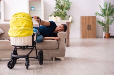 Genç baba yeni doğan bebeğe bakıyor.