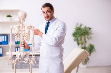 İskeleti olan genç erkek doktor.