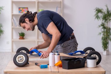 Kaykay tamir eden genç bir erkek tamirci.