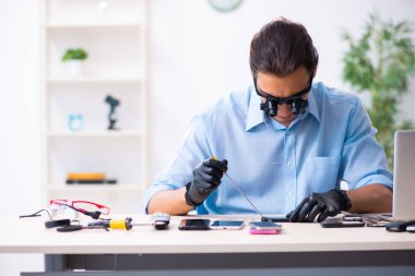Cep telefonunu tamir eden genç bir teknisyen.