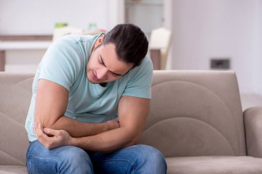 Evde acı çeken yaralı genç adam.