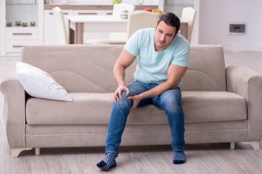 Evde acı çeken yaralı genç adam.