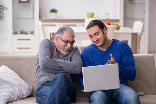 Baba oğul kanepede bilgisayar başında oturuyor.