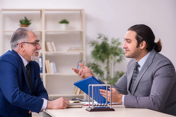 Masada iki iş adamı ve meditasyon topu var.