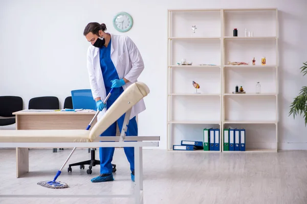 Ung manlig entreprenör desinficera klinik i pandemi koncept — Stockfoto