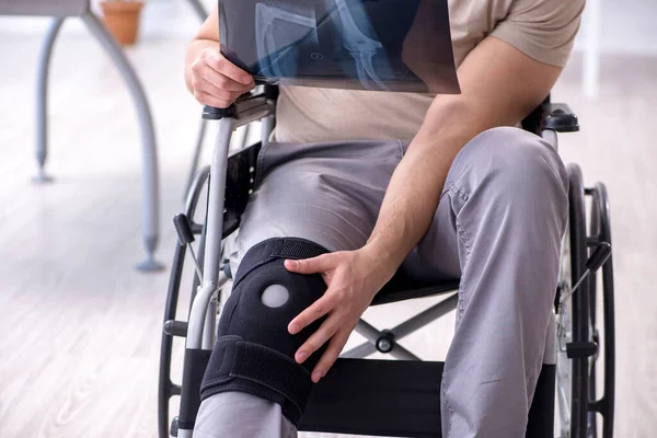 Tekerlekli sandalyedeki yaralı genç adam röntgene bakıyor.