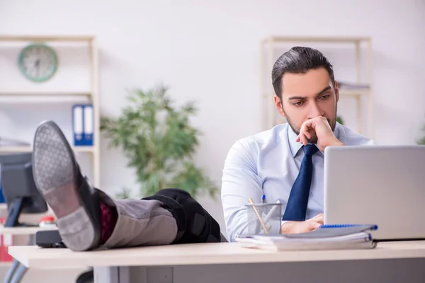 Young leg injured employee working in the office — Stock Photo, Image