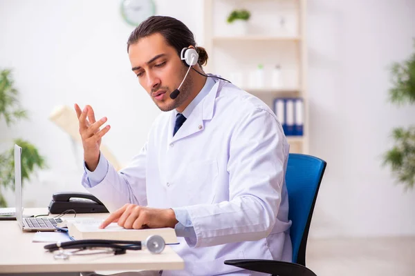 Joven médico escuchando al paciente durante la sesión de telemedicina —  Fotos de Stock