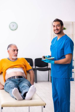 Yaşlı adam genç erkek doktoru ziyaret ediyor.