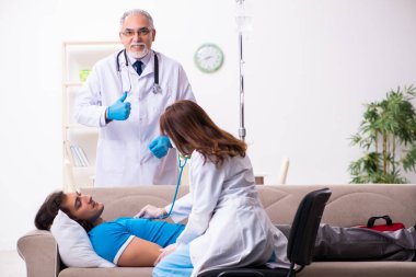 İki doktor hasta bir genci ziyaret ediyor.