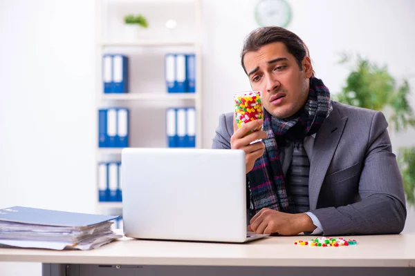 Jonge mannelijke werknemer die op het werk lijdt — Stockfoto