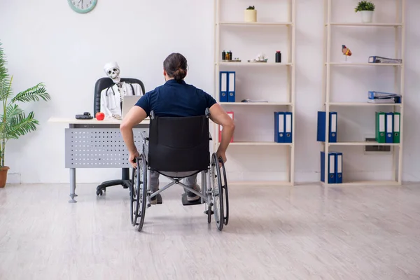 Młody człowiek na wózku inwalidzkim odwiedza martwego lekarza — Zdjęcie stockowe