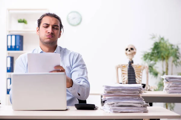 Young male employee and skeleton in the office — Stock Photo, Image