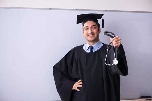 Young male graduate in front of board — Stock Photo, Image