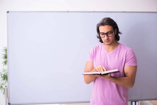 Young male student in front of board — Stock Photo, Image