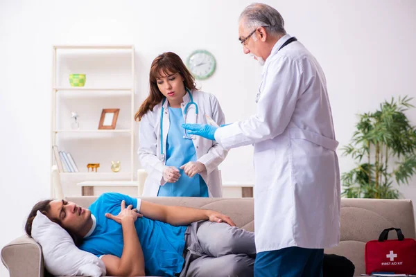 İki doktor hasta bir genci ziyaret ediyor.