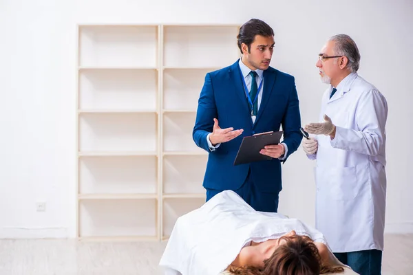 Police coroner examining dead body corpse in morgue