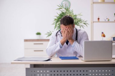 Klinikte çalışan genç erkek doktor.