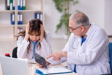 Yaşlı erkek doktor radyoloji uzmanı ve genç bayan asistanı.