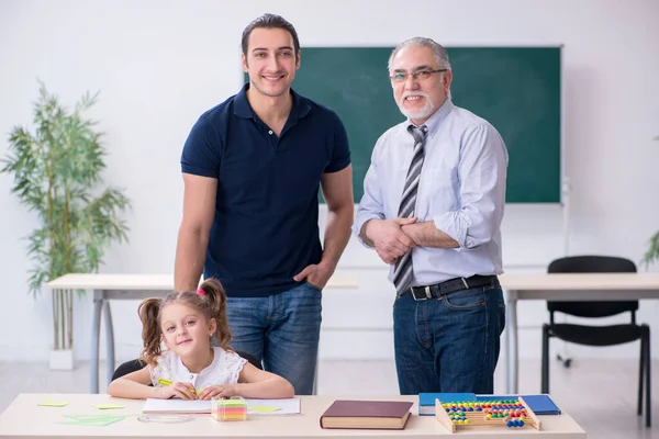 Молодой родитель, старый учитель и маленькая девочка в классе — стоковое фото