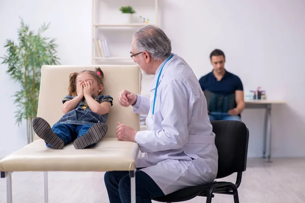 Jonge vader en zijn dochter op bezoek bij oude mannelijke arts — Stockfoto