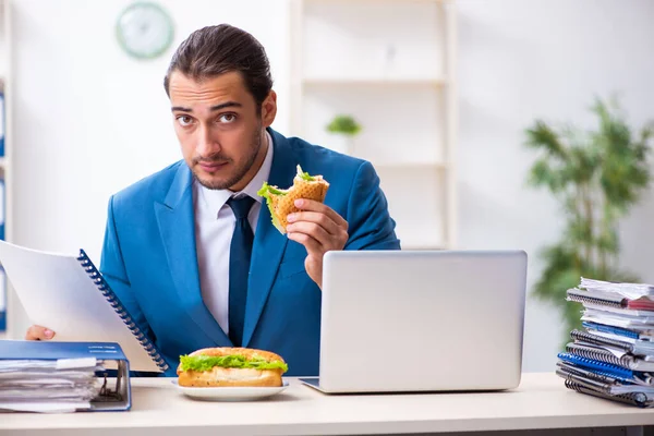 Jeune employé masculin prenant son petit déjeuner sur le lieu de travail — Photo