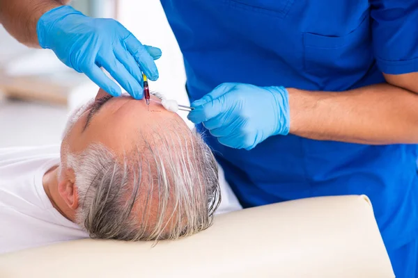 Vieil homme visitant jeune médecin masculin en conce de transplantation de cheveux — Photo