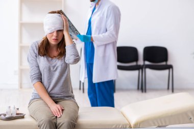 Genç baş yaralı kadın genç erkek doktoru ziyaret ediyor.