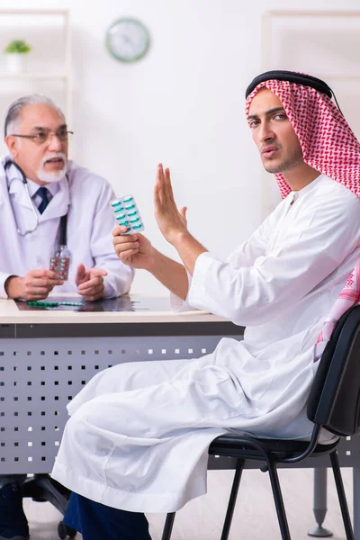 Young male arab visiting experienced male doctor — Stock fotografie