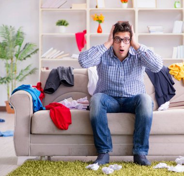 Genç adam dağınık bir odada çalışıyor.