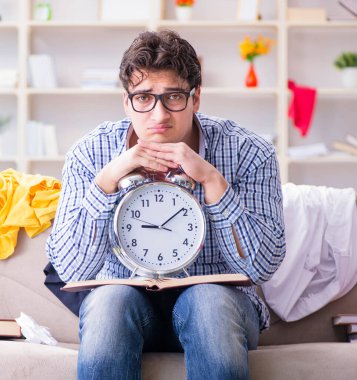 Genç adam dağınık bir odada çalışıyor.